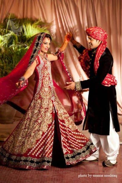 This bridal stands out due to its uniqueness and the perfect fusion of modern cut and traditional embroidery. Deep red pure chiffon front open gown features stunning embellishment all over the front. This super stunning shirt is made of rich floral embroidery which is further enhanced with zardoze work. Hemline is decorated with embroidered black applique and banarsi patch at the end. Matching deep red dupatta. Dupatta contains embroidered border on four side edge and lighter work on the ground.