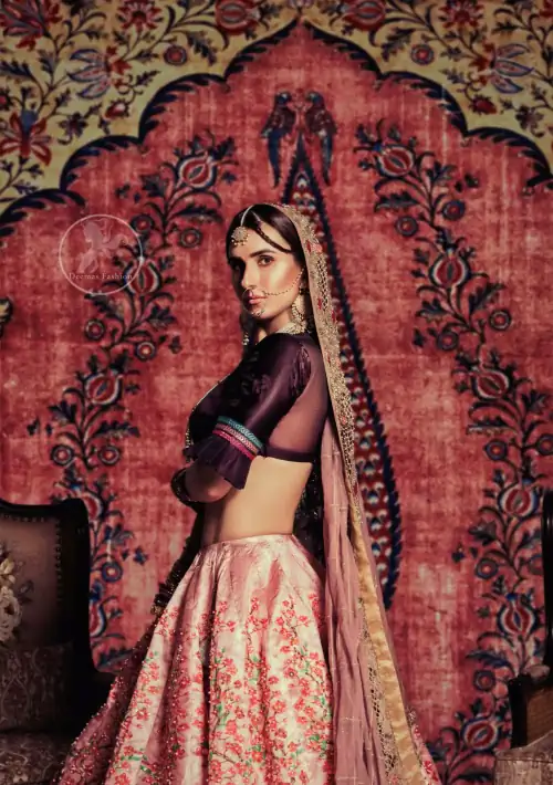 This outfit is a timeless beauty. Dark purple self-printed blouse is decorated with applique. The raw silk classic lehenga is
