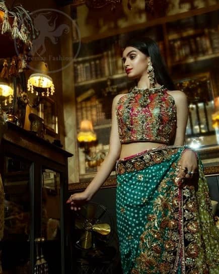 This outfit is a timeless beauty. It is heavily embellished with antique gold kora, dabka, tilla, sequins and swarovski crystals. This exquisite halter neckline blouse is fully decorated with floral motifs patterns all over it. Applique waist belt is decorated with gota and thread embroidery.It comes with embellished lehengha. This Outfit is beautifully coordinated with lime yellow dupatta with heavy embroidered borders.