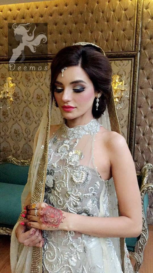 This outfit is a timeless beauty. It is heavily embellished with silver kora, dabka, sequins and swaronski crystals. This exquisite A-line frock is fully decorated with floral motifs patterns all over it. It is further enhanced with halter neckline.It comes with sharara which has small sized sprinkled floral motifs all over. This Outfit is beautifully coordinated with matching dupatta with heavy embroidered borders and finished with piping.