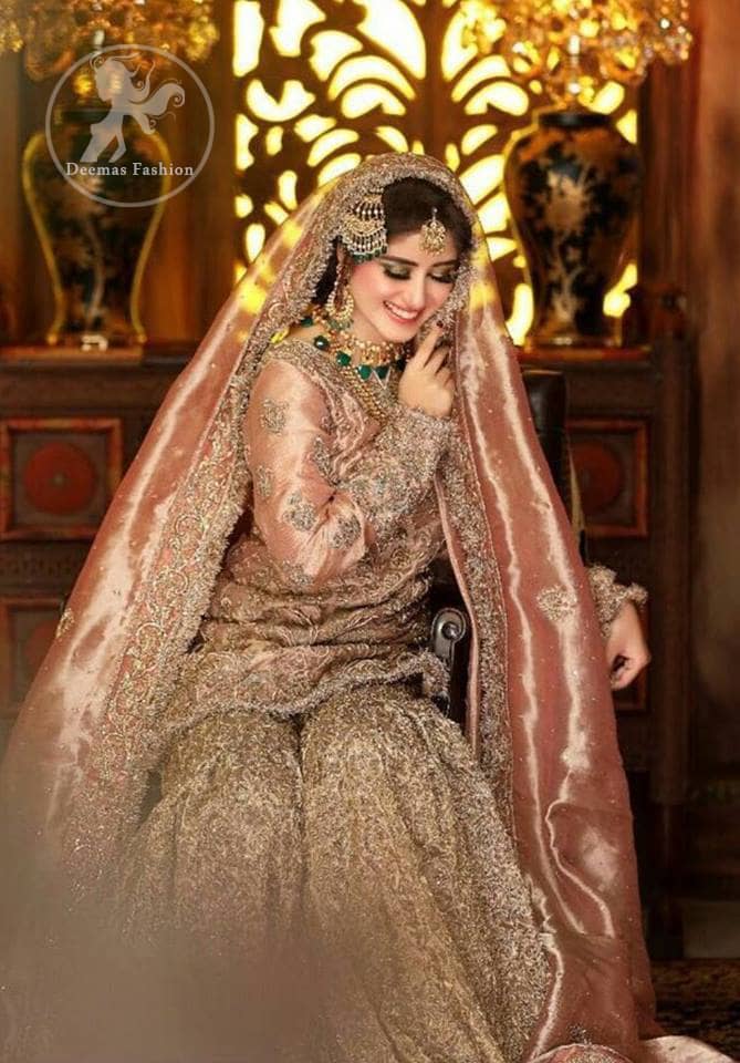 Feel glamorous in antique brass short shirt with fascinating embellishment on neckline with golden kora dabka, tilla and pearls. Floral motifs on sleeves add to the look. It is stunningly coordinated with traditional golden gharara. Complete the look with tilla work organza dupatta finessed with embroidered borders.