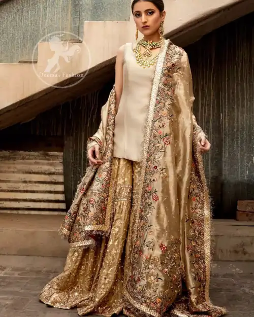 Ivory plain shirt is paired up with golden traditional gharara done with floral motifs all over. It is beautifully matched