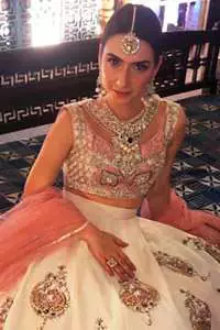 The blouse is beautifully embellished with cutwork embroidery enhanced with silver gold kora dabka, kundan and sequins work. It is paired up with ivory lehenga with colorful pattern embellishment ornamented with kora dabka, and colorful thread embroidery. It comprises with peach dupatta sprinkled sequins all over.