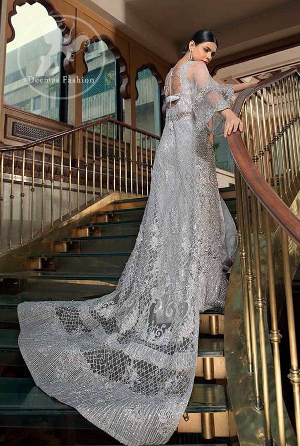 This dress is timeless beauty. Light gray, dress with heavy embellishment with swarovski crystals and silver work in sequins, kundan and kora dabka. The back trail is allured with intricate embroidered patterns and floral motifs. It is finished with light gray sharara.