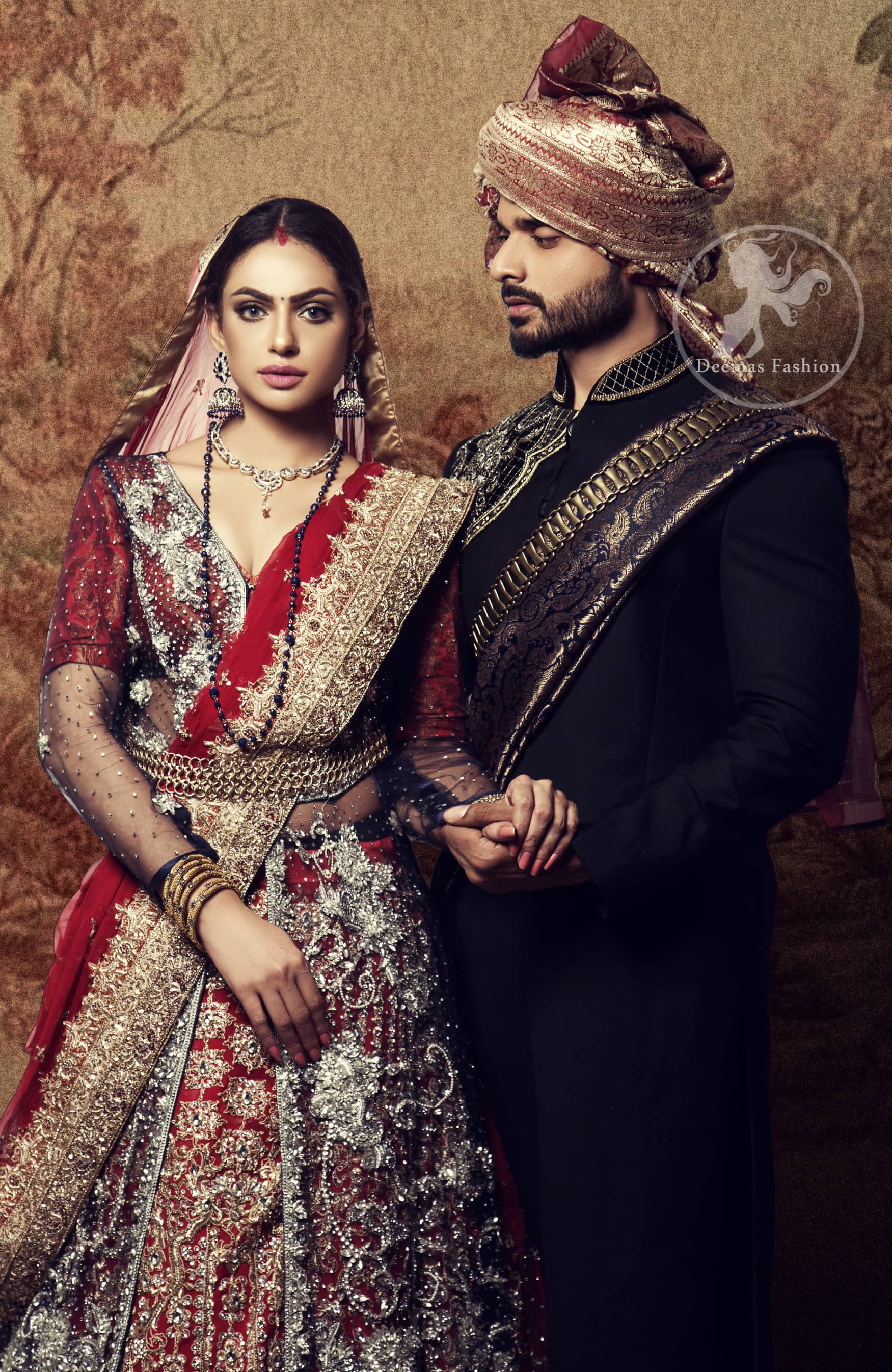 This dress is timeless beauty. Black floor length net paneled gown is beautifully embellished with silver kora dabka, tilla, pearls and sprinkled sequins all over. It comprises with maroon blouse and skirt. The skirt is ornamented with floral motifs done with silver gold kora dabka, tilla, kundan and sequins work. This outfit is coordinated with maroon dupatta with embroidered borders on all four sides and sequins work on the ground.