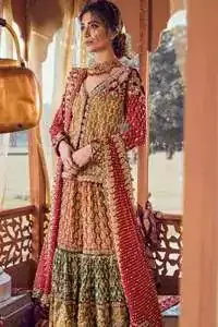 Exquisite detailing radiates elegance in this stunning short shirt. Redefine your style in this traditional and versatile ensemble ornamented with floral and geometric embroidery furnished with golden kora dabka, kundan and pearls. It comes with multiple colored traditional gharara done with zerdozi work in patterns and embroidered applique details on bottom. Complete the look with red dupatta having embroidered borders on all sides and sequins spray on the ground.