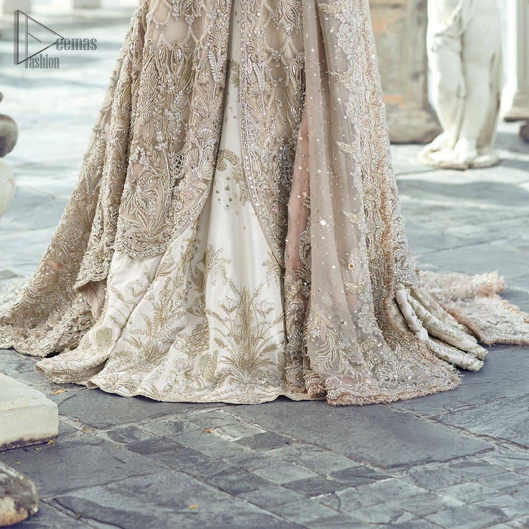 Captured in traditional silhouette, The bridal stands out due to its uniqueness and the perfect fusion of modern cut and traditional embroidery. It is highlighted with silver and light golden kora, dabka, tilla, sequins and pearls. It comes with heavily embellished front open back trail gown ornamented with floral embroidered  motifs and geometric patterns. Paired up with ivory lehenga done with light gold embroidery. It is coordinated with chiffon dupatta which is sprinkled with sequins all over it. It is further furnished with four sided border.