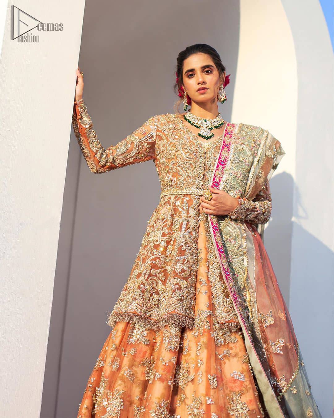 Captured in traditional silhouette, The bridal stands out due to its uniqueness and the perfect fusion of modern cut and traditional embroidery. This front open short frock is highlighted with kora, dabka, tilla, sequins and pearls. It comes with full embellished lehenga adorned with floral bunches, applique on the hemline and sequins spray all over it. It is coordinated with organza dupatta which is sprinkled with tiny floral motifs all over and a thick embellished border on all four sides with applique details.