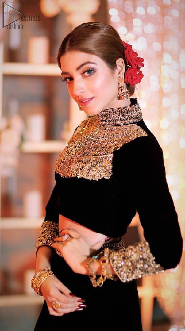 Embrace the season of festivities with this beautiful dress. This elegant ensemble turns timeless piece into a chic fantasy. The halter neck blouse is delicately hand crafted using the finest old age techniques and materials including kora, dabka, tilla, sequins, stones, and crystal. The sleeves are embellished with a thick embroidered border. Lehenga comprises of thick embroidered bottom to give it a regal look. It comes with a black net dupatta with sequins sprayed all over it .