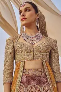 This weeding outfit makes a statement in this stunningly floraison, perfect blend of glamour and tradition with outstanding craftsmanship and gorgeous detailing. Heavily embellished blouse and bottom done with golden zardozi work and detailed central slits instantly draws attention. The lehnga with embroidered motifs spread all over and thick embellishment on lower waist. Paired it up with light pink net dupatta sprinkled with tiny motifs and four sided border.