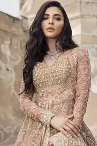 This garnet ensemble is sure to make you look like glamorous royalty with immaculate work covering every inch of the frock. The bodice of the frock is heavily embroidered with champagne zardozi work. Furthermore the hemline is ornamented with geometric patterns. It is coordinated with peach and light pink lehenga with a flowing train embellished with light golden and champagne embroidery and scattered floral motifs in a sequence.  this is an ensemble that deserves to be flaunted. Style it up with light pink dupatta having four sided embroidered border.