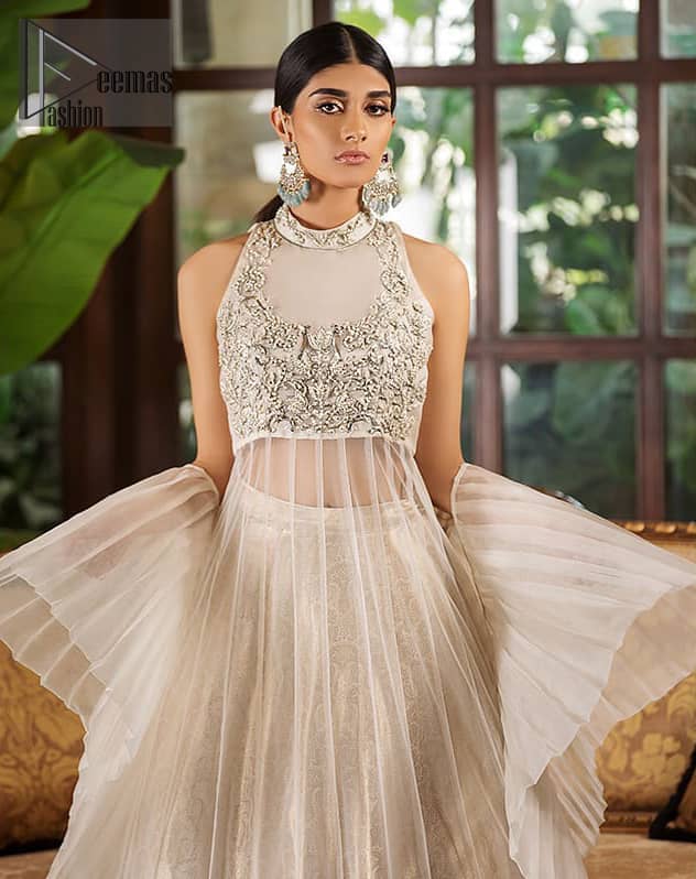 This halter neck frock is majestic beauty. Delicately crafted and personifying chic elegance with an element of grandiose. A full heavily embroidered bodice done with silver and gray zardozi work. The bottom of the frock is enhanced with rich floral embroidery and wide hemline. It comprises with brocade lehenga and net frilled lift the whole lehenga bottom. Complete the look with tea rose dupatta sprinkled with sequins on all over the ground.