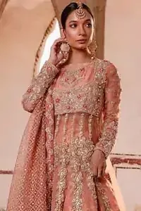 You are all set to make a lasting impact with the divine royalty of this dress. This garment is sure to make you look like glamorous with immaculate work covering every inch of the pishwas with multiple panels. This pishwas made of zardozi work with scalloped hemline and applique is everything that you need for your festivities. The brocade lehenga is beautifully adorned with thick embellished bottom with zardozi work in the shades of silver and gold. Style it up with peach organza dupatta with criss-cross patterns and floral booties on borders. This is an ensemble that deserves to be flaunted.