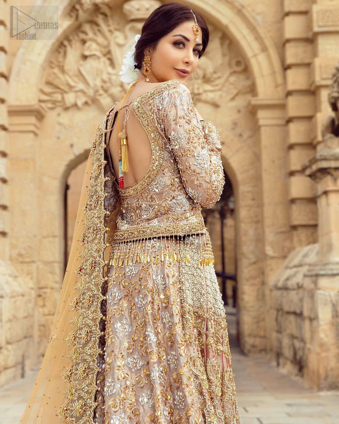 Strike a breathtakingly elegant pose in this wedding dress, designed with a beautiful blouse and a dramatic train. This artisan piece includes intricate hand-embellishment. This highly skilled technique involves hand needle work to add beads, kora, dabka, tilla and sequins to the fabric, giving our garments a unique look. The blouse is also enhanced with tassels on the hemline and back is adorned with horse shie neckline. Zardozi work is done in the shades of golden and silver. Dupatta is decorated with sequins spray on the canvas and finished with embroidered border on four sides which makes this outfit more beautiful.
