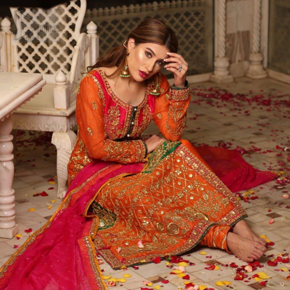 Get bold and beautiful with this uber-stylish ensemble that has flattering cuts, and a colour palette that is bewitching.  This orange long shirt adorned with intricate tilla work, kora, dabka and sequins is perfect ensemble for mehndi. Furthermore the shirt is also highlighted with pink embellished bodice and rest of the shirt is enhanced with geometric gota embroidery and green applique instantly draws attention.. It comprises with orange pajama adorned with gota work. Paired with pink chiffon dupatta with kiran lace finishing all around the edges that gives the right amount of glamour to the outfit.