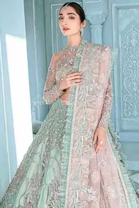 A enchanting amalgamation. This fairytale ensemble is everything that you need to impress everyone. The fusion of rich fabrics intricately designed with floral powdery hue. Precious uncut stones are threaded together with silver zardozi on pastel color palette to give it an enchantingly exquisite look. The illusion neckline blouse is laden with silver kora, dabka details and pair it up with a beautiful lehenga. The lehenga is adorned with colorful chatta patti waist belt and a captivating geometric jaal finished with scattered floral motifs and scalloped hemline. Finish the look with pink dupatta focusing on heavily embellished borders on all four sides to give it a perfect maharani look.