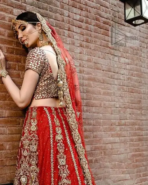 On your perfect day, let all admire your elegance with Red Ruffled Back Train Lehenga Blouse. A red half-sleeved traditional