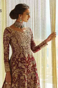 Serving a bold and funky style affair perfect for the big day. Stun in this classic base with contemporary golden adornment serving an elevated style. Detailing of the deep red frock is starting from the delightful and charming golden embroidery which is highlighted with tilla, zardozi, dabka and pearls. The V shape neckline of the frock is as lovely as you can see in the picture. Further, the bottom of the frock is enhanced with the scalloped border as well. It is arranged with the same colour lehenga that is also ornamented with heavy golden embroidery. Finally, end up this outfit with a deep red dupatta which is embellished with a four-sided border and sequins spray all over.