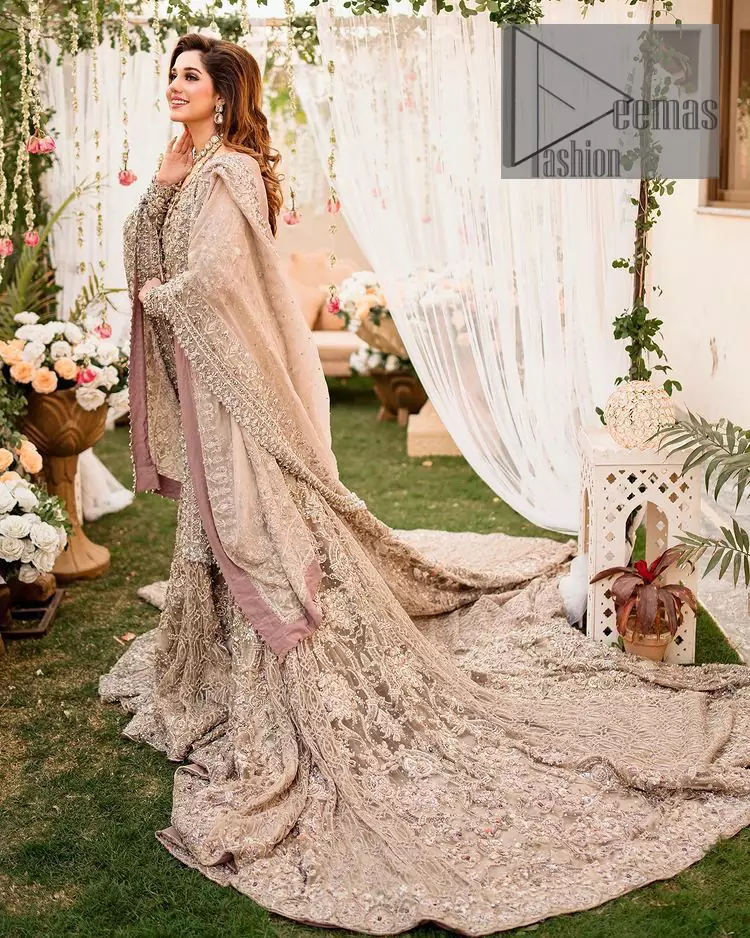 Embrace happiness on your Walima in the colour of beige-pink along this dreamiest fairy tail maxi. The floral fusion of tilla and thread embroidery on a royal beige-pink maxi is to fulfil your dreamy look. The boat shape neckline of this maxi is as amazing as the whole maxi. Further, it is fully embellished with tilla, kora, dabka and sequins work just to enhance the beauty of your Walima day. The fairy tale is also adorned with heavy work and looks super amazing when combine with full sleeves style. Finish this fairy look with the same colour dupatta that is ornamented with a four-sided border and sequins sprayed all over to increase the look of this article.