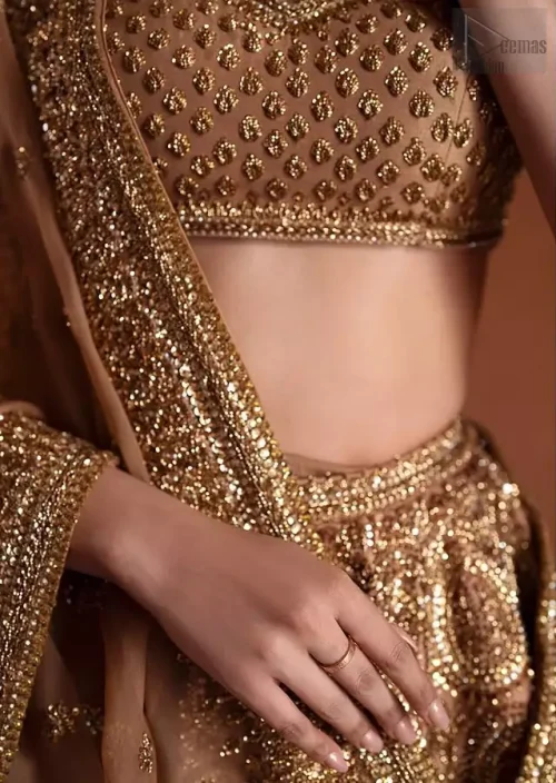 A striking look at the lower lehenga hemline, dominated by a heavy, sculptural antique border rich with layered zardozi, stones, and shimmering crystals.